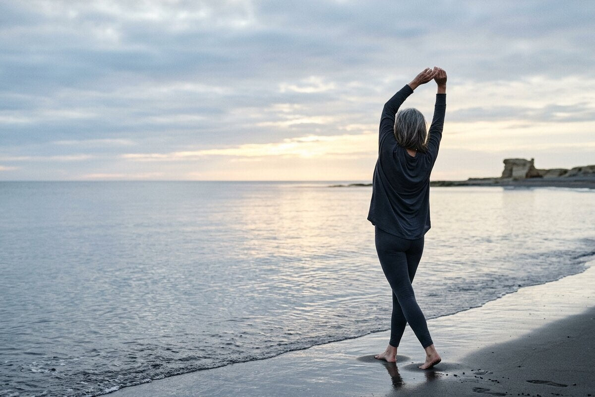 夜明けの浜辺でストレッチをする女性の後ろ姿