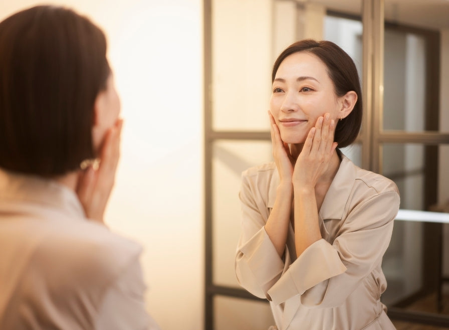 鏡の前で頬に手を添える女性